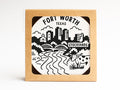 The Fort Worth Texas Skyline Letterpress Coaster Set by Onderkast Studio features black and white cityscape, river, bridge, cow, and Stockyards sign designs in letterpress style, packaged in a recyclable kraft box with a clear window.
