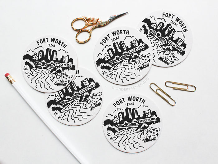 The Fort Worth Texas Skyline Letterpress Coaster Set by Onderkast Studio is displayed on a white surface with gold scissors, paperclips, and a pencil—ideal inspiration for your next creative project.