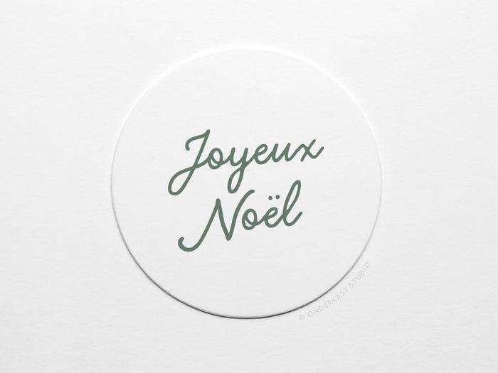 The Joyeux Noël Coaster Set by Onderkast Studio features white circular pulp board coasters with Joyeux Noël handwritten in green script, centered on a plain white background.