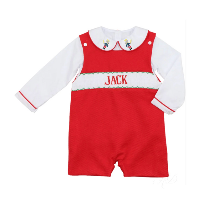 A baby romper with a red body, white long sleeves, and a white collar, featuring 'JACK' embroidered in red across a green and white chest band. The romper is laid flat on a white background.