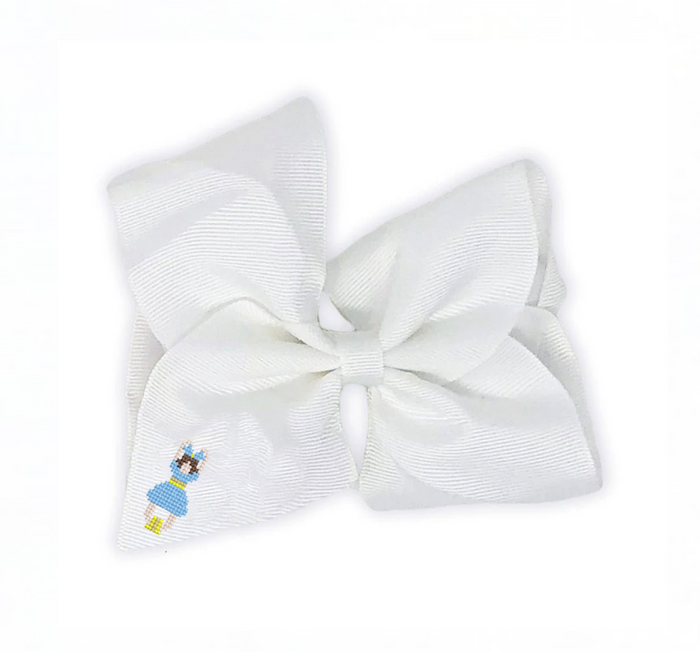 A large white grosgrain ribbon hair bow featuring a small embroidered cartoon girl in a blue dress on the lower left loop, set against a plain white background.